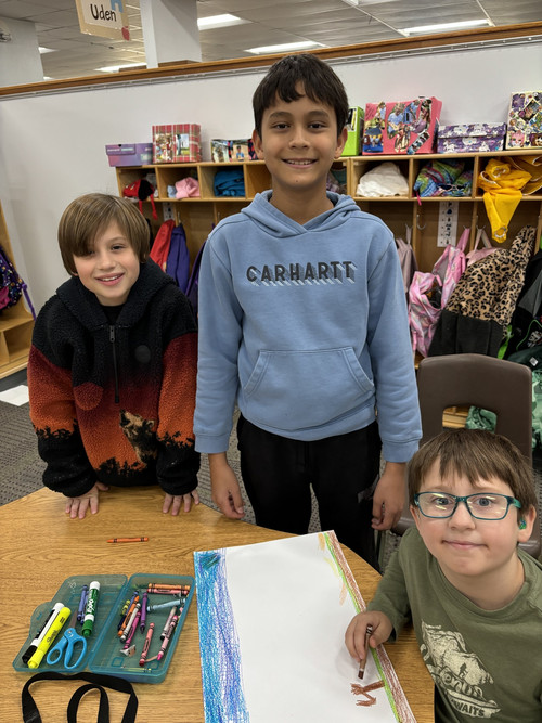 Three students working together on a worksheet posing for the camera.