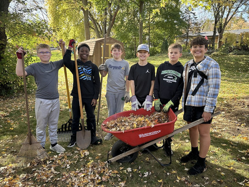 Students standing together around wheelbarrow in neighbors yard on Clean & Green day.